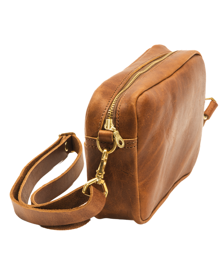 Brown leather bag with gold zipper on a white background #color_brown