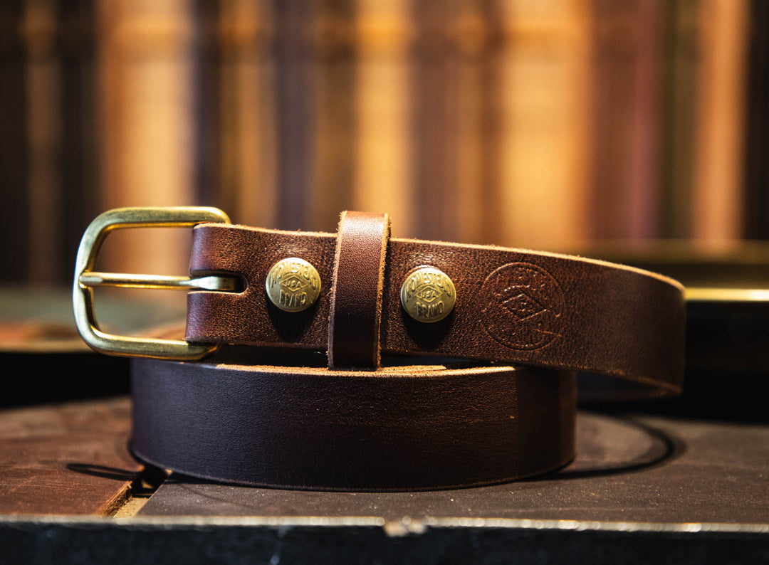 Brown leather belt with gold buckles on a wooden surface #color_brown