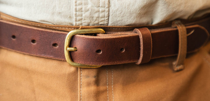 Brown leather belt with brass buckle on beige pants #color_brown