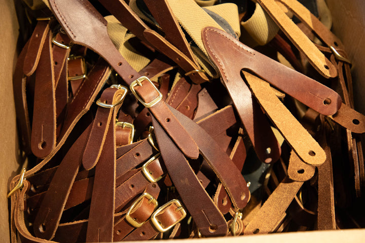 Collection of brown leather straps with gold buckles in a box