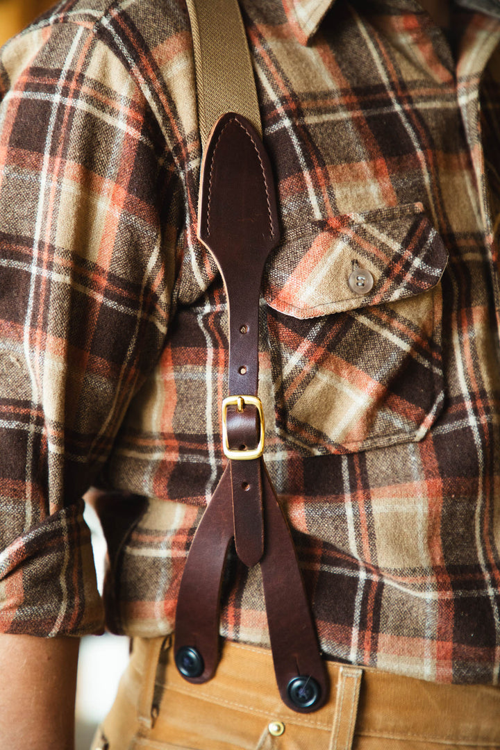 Brown leather suspenders on a plaid shirt