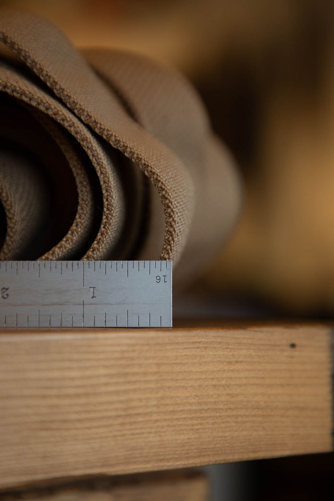 Brown leather roll with a ruler for scale on a wooden surface